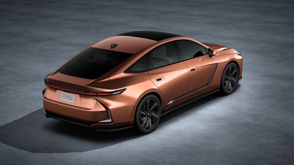 A sleek, bronze-colored Lexus ES 500h hybrid sedan with a modern design is displayed on a gray surface, highlighting its aerodynamic rear and stylish black wheels.